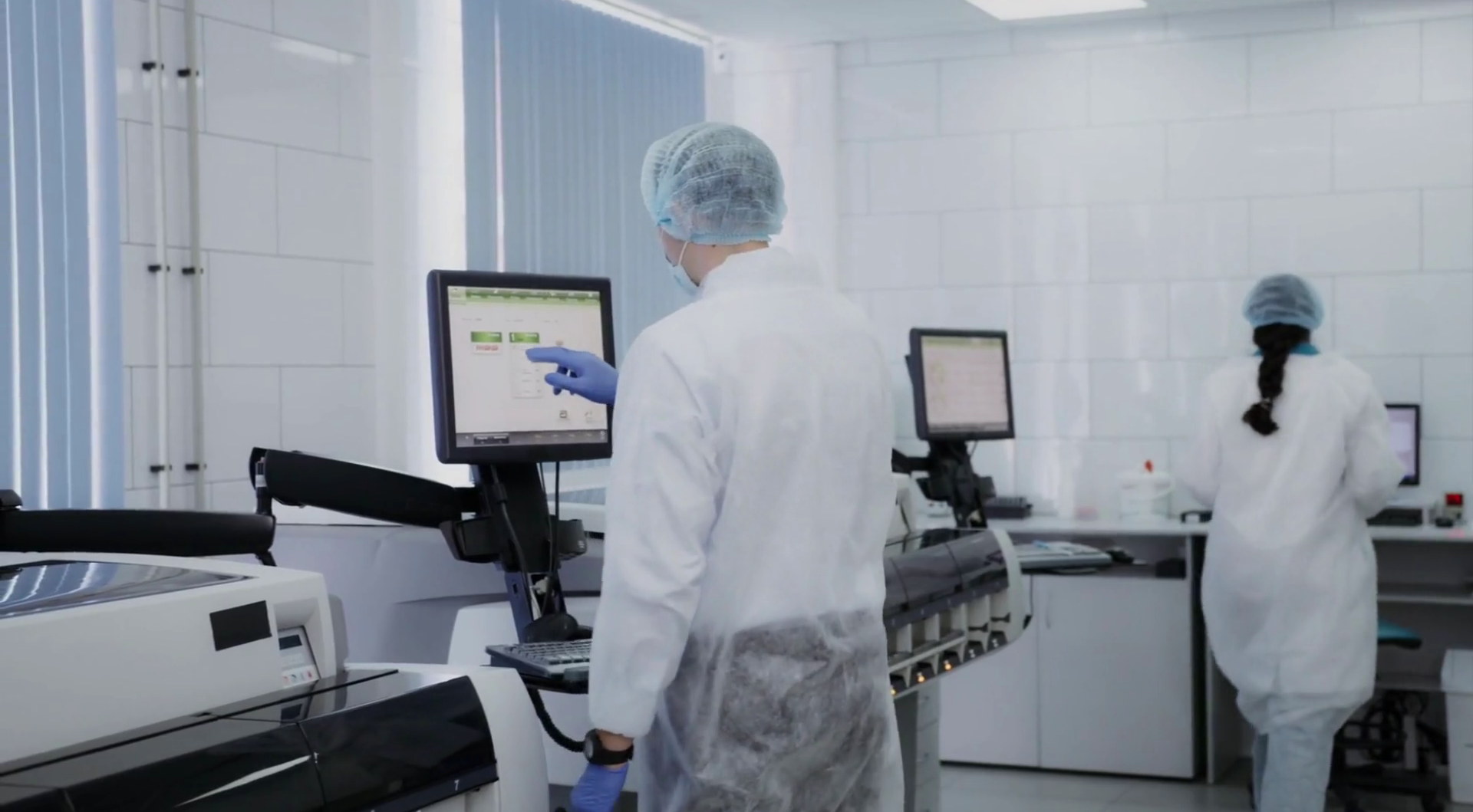 A researcher checking an inspection monitor in a cleanroom